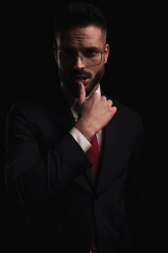 sexy bearded businessman wearing black elegant suit and touching lips