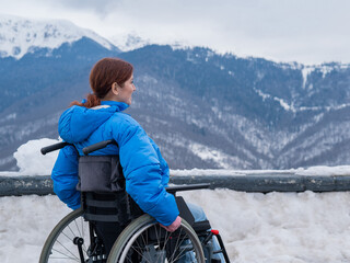 Caucasian woman in a wheelchair travels in the mountains in winter.