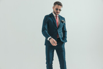 happy elegant man in suit with glasses holding hand in pocket and stepping
