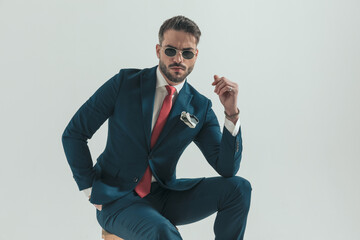 serious young man in suit with hand in pocket wearing retro sunglasses