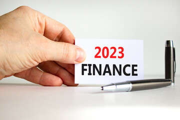 2023 Finance symbol. White paper with words 2023 Finance. Businessman hand. Metallic pen. Beautiful white table white background. Business and 2023 finance concept. Copy space.