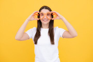 Portrait of a funny girl wearing cool party glasses. Cheerful young girl smiling with heart-shape glasses on yellow background.