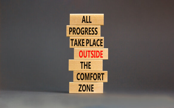 Progress symbol. Concept words All progress take place outside the comfort zone on wooden blocks on a beautiful grey table grey background. Business motivational and progress concept.