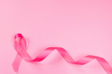 Pink ribbon on colored background. Breast Cancer Awareness Month symbol. Women's health care concept. Promotion of campaign to fight cancer.