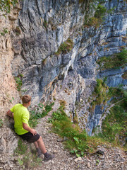 Boy at top of path with steel chain anchored in the rocky wall
