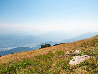 Summer meadow at Gazza mountain, blue sky and high peaks.