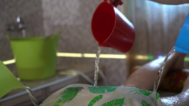 The beautician makes a chocolate massage to a young man in a luxury spa. Masseur washes chocolate from back with water.