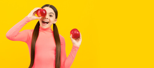 happy kid with red apple on yellow background, vitamins. Child girl portrait with apple, horizontal poster. Banner header with copy space.