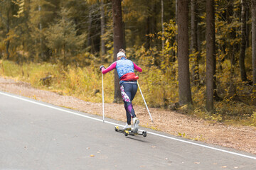 Cross country skilling.A woman on roller skis rides in the autumn park.
