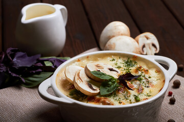 Chicken julienne with cheese, mushrooms and herbs in white plate on wooden board