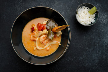 Thai soup with seafood and rice, on dark concrete
