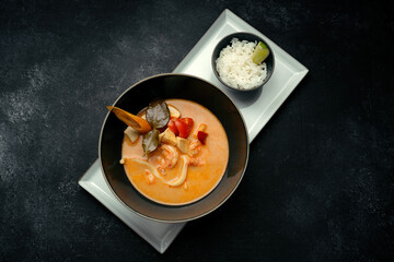 Thai soup with seafood and rice, on dark concrete