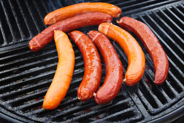 Traditionelle deutsche Bratwurst vom Grill angeboten als close-up auf einem Holzkohlegrill mit...