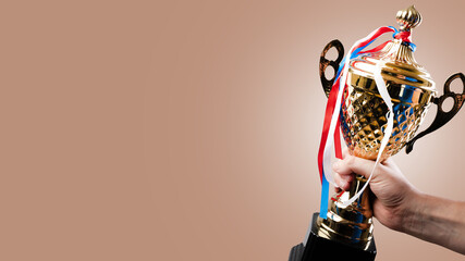 Golden sports cup and medals on multi-colored ribbons on the cup. Award for sporting achievements, success, victory, holiday. There are no people in the photo. There is free space to insert.