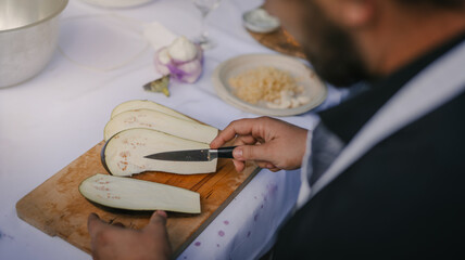 Close up photo of male hands is preparing wonderful fresh eggplant salad. Chef cooking food cutting prepare hands knife preparing eggplant.