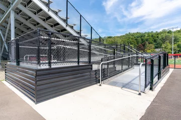 Fotobehang Accessible wheelchair ramp with railings and slip resistant surface at empty metal stadium bleacher.  Nondescript location with no people in image.  Not a ticketed event.    © Thomas