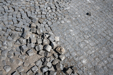 damaged road paved with setts. Loose paving stones in a cobblestone street. 
