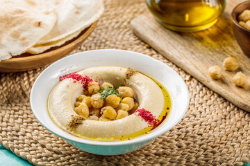 Hommus with chick peas served in a dish isolated on wooden table side view of middle eastern food