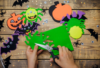 How to make a decor for congratulations and fun on Halloween. Women's hands make crafts from felt and other materials. A green spider for Halloween. Handmade toys.Step 2. Cut out the spider shape.