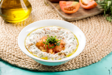 Naklejka premium Hommus Beiruti with tomato served in a dish isolated on wooden table side view of middle eastern food