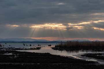 Sunrays at near sunset, with dark clouds in the background, above Trasimeno lake, Umbria, Italy