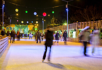 People are skating in the park on winter skating rink - 529897356