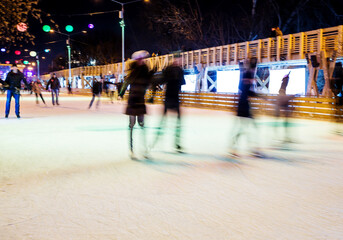 People are skating in the park on winter skating rink