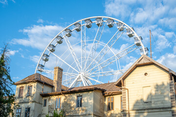 Ferris wheel detail and the part of the house in front against blue sky in Keszthely, Hungary