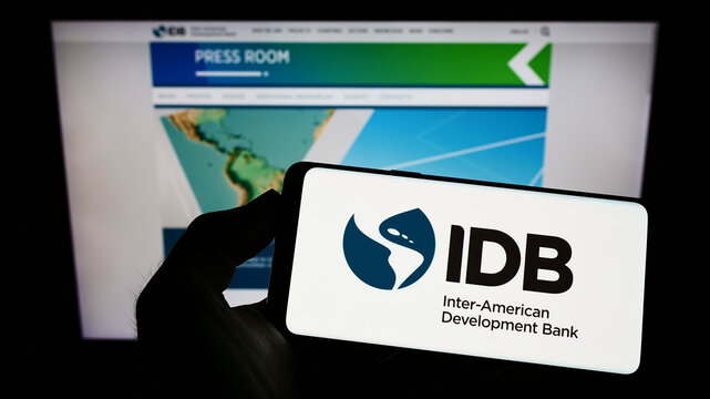 Stuttgart, Germany - 07-09-2022: Person holding mobile phone with logo of Inter-American Development Bank (IADB) on screen in front of business web page. Focus on phone display.