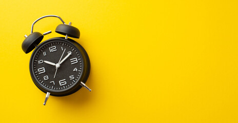 Black friday concept. Top view photo of black alarm clock on isolated yellow background with empty space