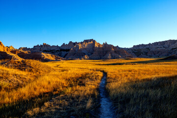 Trail through prairie grass with distant badlands rock formation