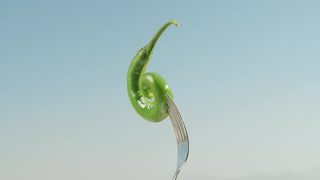 Green pepper impaled on a fork, rotates against a background of blue sky. close-up