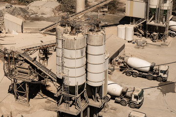 An active concrete plant also called a batching plant with trucks being loaded with fresh mix made...