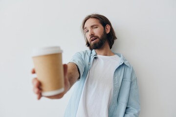 Freelance Millennial man with a beard drinking coffee from a recycled cup in stylish hipster clothes white T-shirt blue jeans and shirt on a white background