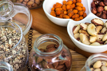 Rustic wood table filled with a large assortment of nuts like pistachios, hazelnut, pine nut, almonds, pumpkin seeds, sunflower seeds, peanuts, cashew and walnuts