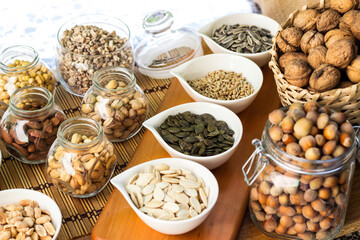 Rustic wood table filled with a large assortment of nuts like pistachios, hazelnut, pine nut, almonds, pumpkin seeds, sunflower seeds, peanuts, cashew and walnuts