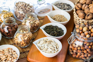 Rustic wood table filled with a large assortment of nuts like pistachios, hazelnut, pine nut, almonds, pumpkin seeds, sunflower seeds, peanuts, cashew and walnuts