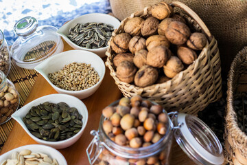 Rustic wood table filled with a large assortment of nuts like pistachios, hazelnut, pine nut, almonds, pumpkin seeds, sunflower seeds, peanuts, cashew and walnuts