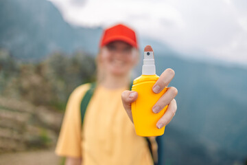 Young woman travel spraying insect repellents on skin with spray bottle during hike in nature top mountain. Skin protection against insect bite.  © Shi 