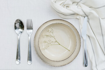 tableware and silverware setting on white tablecloth, top view