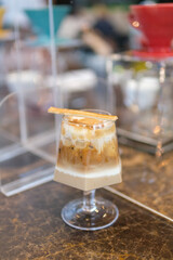 selective focus, glass of Iced coffee with milk, caramel syrup in coffee shop. cold latte coffee in cup on wooden table in cafe with sunlight background