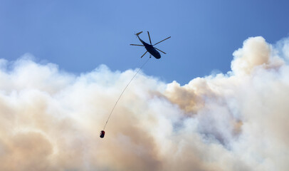Wildfire Service Helicopter flying over BC Forest Fire and Smoke on the mountain near Hope during a hot sunny summer day. British Columbia, Canada. Natural Disaster