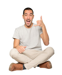 Amazed young man making a gesture of calling with the hand