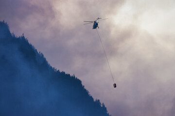 Wildfire Service Helicopter flying over BC Forest Fire and Smoke on the mountain near Hope during a...