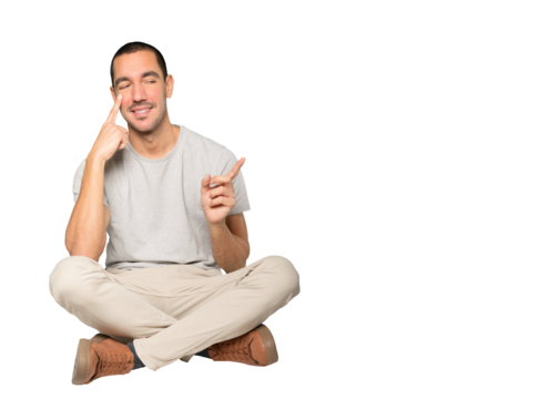 Friendly young man making a gesture of being careful with his hand pointing at his eye