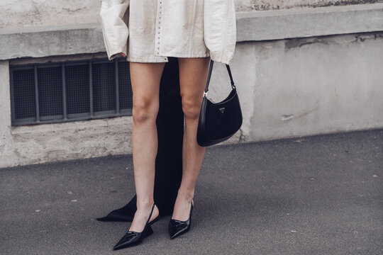 Street style, woman wearing cream leather jacket, mini skirt with long train, black Prada bag and Prada heels.