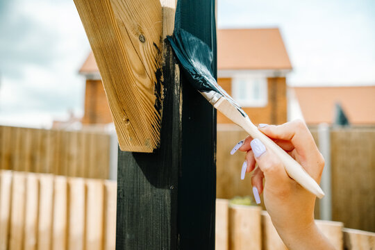 Person Painting A Wooden Fence