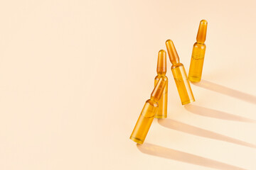 Cosmetic ampoules with serum on cream-coloured beige background with shadows and caustic. Beauty hair, Rejuvenation and cosmetics for skin care. Concept Self-care, spa and wellness. Copy space.