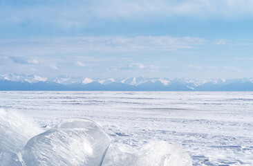 Fototapeta na wymiar Winter landscape with ice hummocks glittering in the sun and mountains of Lake Baikal in Siberia at sunset. Natural background.