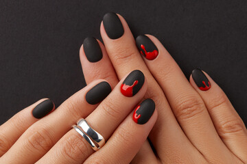 Manicured female hands with fashion accessories on black. Trendy autumn halloween bloody spooky...